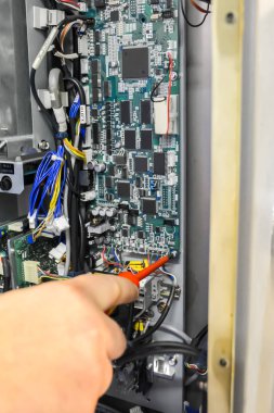 Elektronik pano onarın. Kaldırma kontrol kurulu için yenisiyle değiştirme, denetleme ve onarma. Bir tornavida ile cıvataları sökün. Endüstri kavramı.