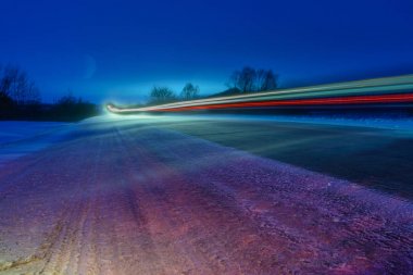 Beyaz ve kırmızı çizgiler şeklinde gece kış karayolu üzerinde araba farlar desenleri. Şiddetli bir kar fırtınası karla birlikte yolu süpürüyor. Tehlikeli bir yol. Kış manzarası.