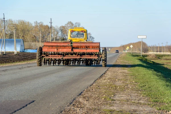 Bir kültivatör ile bir traktör kırsal bir yol boyunca bir ekim kampanyası ile döner. Traktör yolu tamamen kapattı. Yol boyunca büyük ulaşım geçişleri.