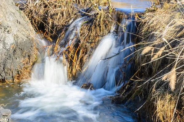 Los tan esperados arroyos de primavera fluyen sobre barrancos y colinas en un día soleado. Rápidos de agua y cascadas de arroyos entre la hierba seca. Paisaje primavera . —  Fotos de Stock