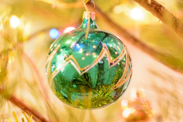 輝く花輪を背景にクリスマスツリーに緑のクリスマス風船 クリスマスツリーの枝に囲まれた緑のボール クリスマスコンセプト — ストック写真