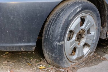 Yakın çekim hasarlı lastik. Araba lastiği sızıntısı. Lastik patlamış, onarılmayı bekliyor. Terk edilmiş araba otoparkta..