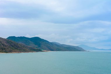Bulutlu bir gün, Güney Çin Denizi 'ndeki tanrıça Nanshan' ın heykelinin yakınında kumlu bir sahil. Sanya, Hainan Adası, Çin. Doğa Manzarası.