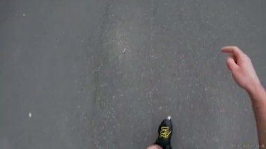 Bir adam sonbahar ormanında asfalt yolda paten kayıyor..