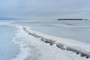 Issız bir ada ve Ulyanovsk yakınlarındaki en geniş ve en derin noktasında donmuş Volga Nehri 'nde büyük bir çatlak. Donmuş bir nehrin, adanın, humuların ve buzun kış manzarası.