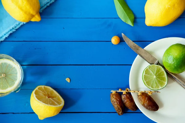 Limes Tarih ve limon ile yaz içki cam mavi ahşap arka plan, limonata malzemeleri kavramı üzerinde