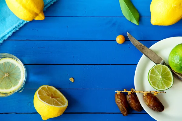 Limes Tarih ve limon ile yaz içki cam mavi ahşap arka plan, limonata malzemeleri kavramı üzerinde