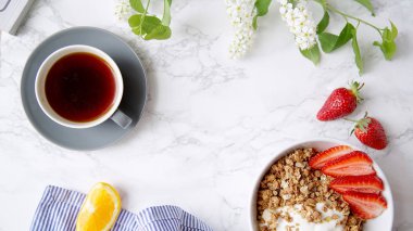Yoğurt ve çilek kase ve mermer masa üzerinde siyah kahve ile gevrek gevrek mükemmel kahvaltı