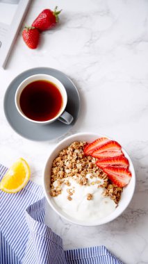 Yoğurt ve çilek kase ve mermer masa üzerinde siyah kahve ile gevrek gevrek mükemmel kahvaltı