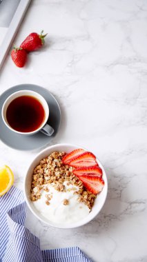 Yoğurt ve çilek kase ve mermer masa üzerinde siyah kahve ile gevrek gevrek mükemmel kahvaltı
