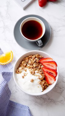 Yoğurt ve çilek kase ve mermer masa üzerinde siyah kahve ile gevrek gevrek mükemmel kahvaltı 