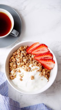 Yoğurt ve çilek kase ve mermer masa üzerinde siyah kahve ile gevrek gevrek mükemmel kahvaltı 