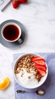 Yoğurt ve çilek kase ve mermer masa üzerinde siyah kahve ile gevrek gevrek mükemmel kahvaltı