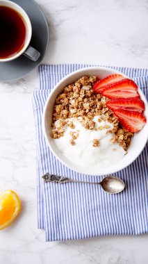 Yoğurt ve çilek kase ve mermer masa üzerinde siyah kahve ile gevrek gevrek mükemmel kahvaltı 