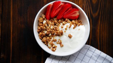 yoğurt ve tahta masada damalı masa örtüsü kase çilek ile lezzetli gevrek gevrek yakın çekim 