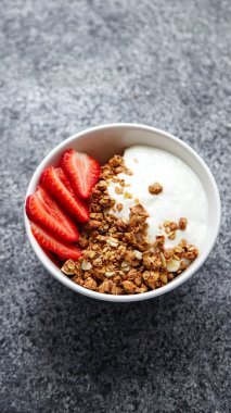 Beyaz kase gevrek gevrek ve gri arka plan üzerinde çilek ile yoğurt ile 