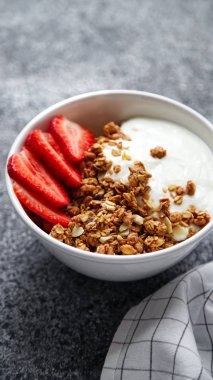 Beyaz kase gevrek gevrek ve gri arka plan üzerinde çilek ile yoğurt ile 