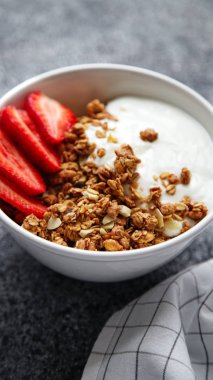 Beyaz kase gevrek gevrek ve gri arka plan üzerinde çilek ile yoğurt ile 