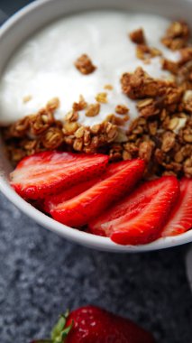 Beyaz kase gevrek gevrek ve gri arka plan üzerinde çilek ile yoğurt ile 