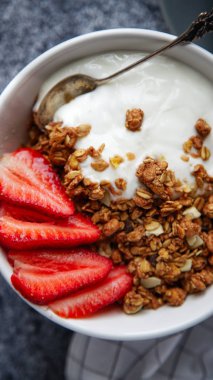 Beyaz kase gevrek gevrek ve gri arka plan üzerinde çilek ile yoğurt ile 