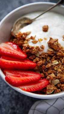 Beyaz kase gevrek gevrek ve gri arka plan üzerinde çilek ile yoğurt ile 