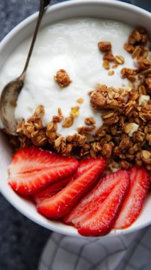 Beyaz kase gevrek gevrek ve gri arka plan üzerinde çilek ile yoğurt ile 