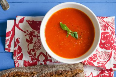 Mavi ahşap masa Çavdar ekmek ile servis fesleğen yaprakları ile süslenmiş domates çorbası 