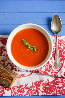 Mavi ahşap masa Çavdar ekmek ile servis fesleğen yaprakları ile süslenmiş domates çorbası 