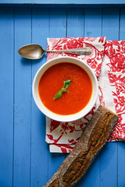 Mavi ahşap masa Çavdar ekmek ile servis fesleğen yaprakları ile süslenmiş domates çorbası 
