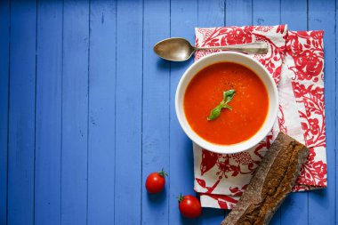 Mavi ahşap masa Çavdar ekmek ile servis fesleğen yaprakları ile süslenmiş domates çorbası 