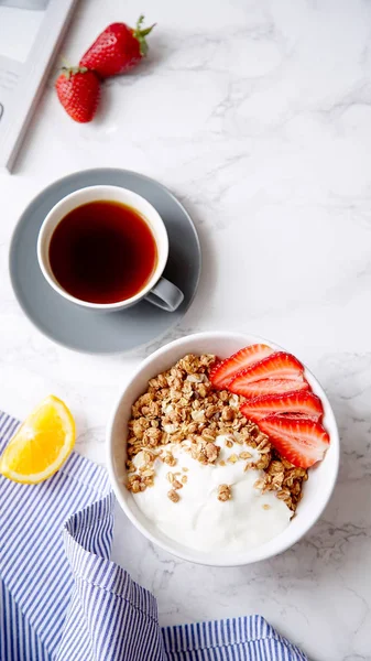 Yoğurt ve çilek kase ve mermer masa üzerinde siyah kahve ile gevrek gevrek mükemmel kahvaltı