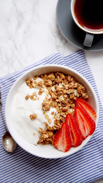 Yoğurt ve çilek kase ve mermer masa üzerinde siyah kahve ile gevrek gevrek mükemmel kahvaltı 