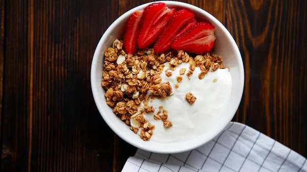 yoğurt ve tahta masada damalı masa örtüsü kase çilek ile lezzetli gevrek gevrek yakın çekim 