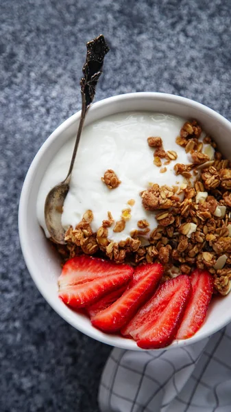 Beyaz kase gevrek gevrek ve gri arka plan üzerinde çilek ile yoğurt ile 