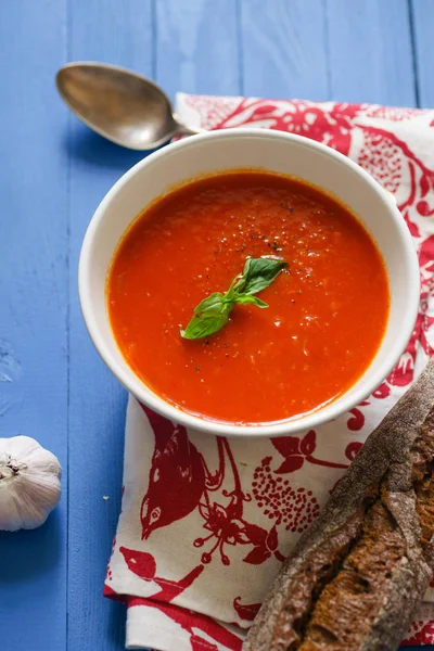 Mavi ahşap masa Çavdar ekmek ile servis fesleğen yaprakları ile süslenmiş domates çorbası 