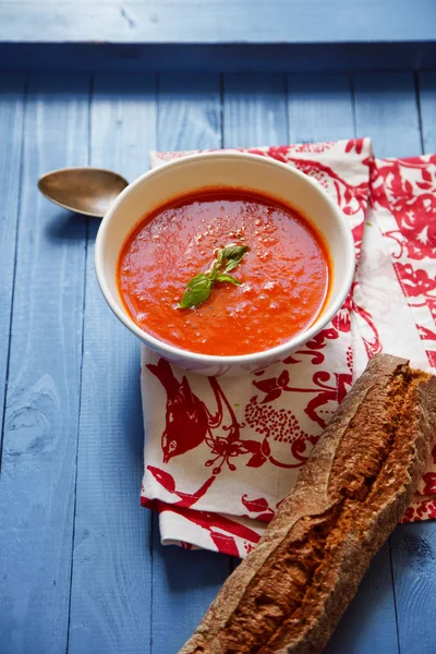 Mavi ahşap masa Çavdar ekmek ile servis fesleğen yaprakları ile süslenmiş domates çorbası 