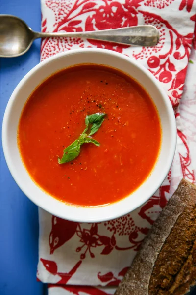 Mavi ahşap masa Çavdar ekmek ile servis fesleğen yaprakları ile süslenmiş domates çorbası 