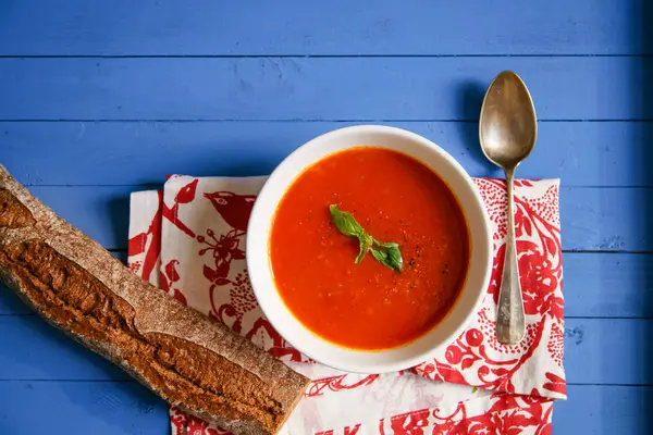 Mavi ahşap masa Çavdar ekmek ile servis fesleğen yaprakları ile süslenmiş domates çorbası 