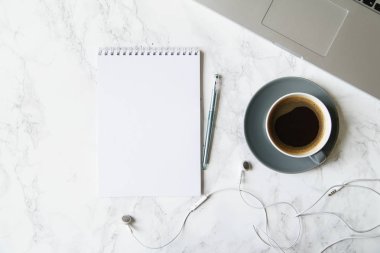 Çalışma alanı ile defter ve laptop ile kahve fincanı ve mermer masa üzerinde kulaklık