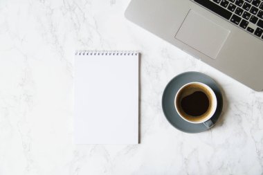 Çalışma alanı ile defter ve laptop ile mermer masada kahve fincanı