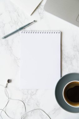 Çalışma alanı ile defter ve laptop ile kahve fincanı ve mermer masa üzerinde kulaklık