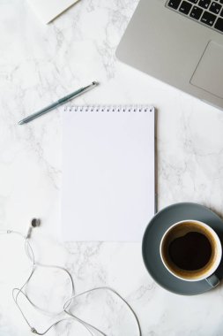 Çalışma alanı ile defter ve laptop ile kahve fincanı ve mermer masa üzerinde kulaklık