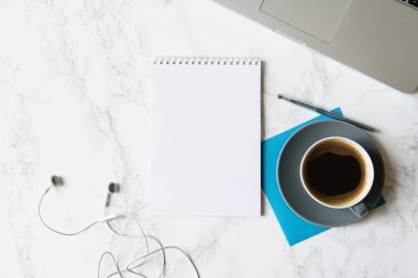 Çalışma alanı ile defter ve laptop ile kahve fincanı ve mermer masa üzerinde kulaklık