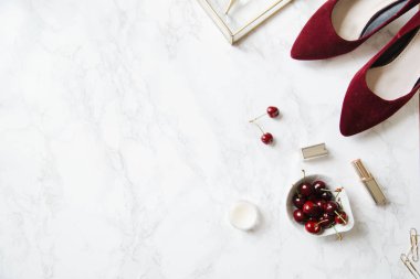 kadınsı aksesuarları ve mermer zemin üzerine kase kiraz kırmızı yüksek topuklu ayakkabılarla