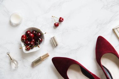 kadınsı aksesuarları ve mermer zemin üzerine kase kiraz kırmızı yüksek topuklu ayakkabılarla