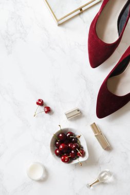 kadınsı aksesuarları ve mermer zemin üzerine kase kiraz kırmızı yüksek topuklu ayakkabılarla