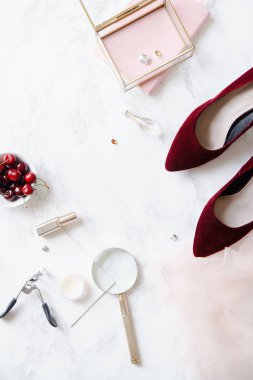 kadınsı aksesuarları ve mermer zemin üzerine kase kiraz kırmızı yüksek topuklu ayakkabılarla