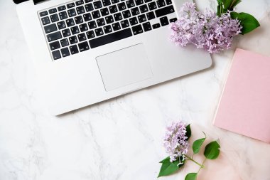 Kadınsı çalışma alanı mock-up mermer zemin üzerine dizüstü klavye ve eflatun çiçekli 