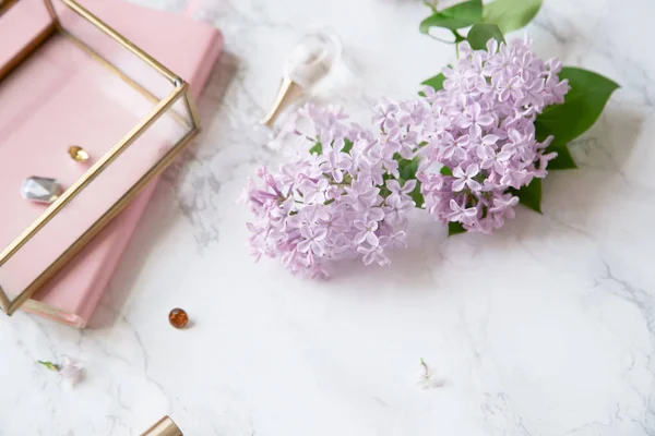 フェミニンなワークスペース モックアップとライラックの花と大理石の背景にピンクのアクセサリー — ストック写真