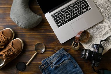 Laptop ile kamera ve büyüteç ile eski vintage ahşap masa, blogger çalışma alanı kavramı üzerinde erkek ayakkabı